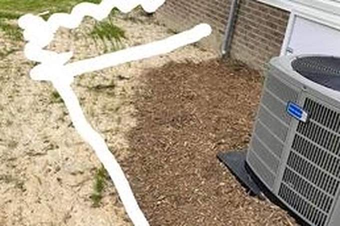 Bare mulch bed beside a brick home with the curb line sprayed onto the ground in white paint