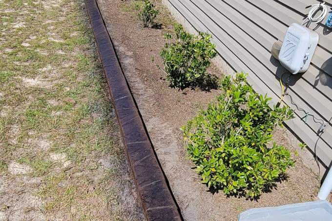 The same bed edged with a long run of wood-grain stamped concrete curbing in a deep brown finish