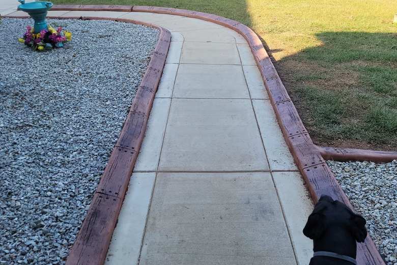 Rust-colored concrete curbing separating a gravel bed from a concrete walkway