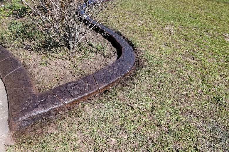 Curved concrete curb wrapping a shrub bed at the corner of a house