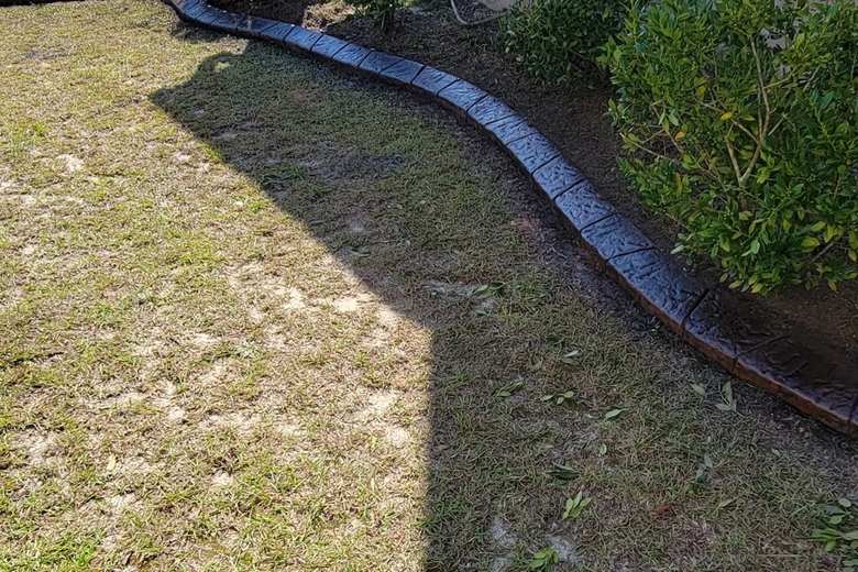Long run of stamped concrete curbing following the side of a home to the back yard