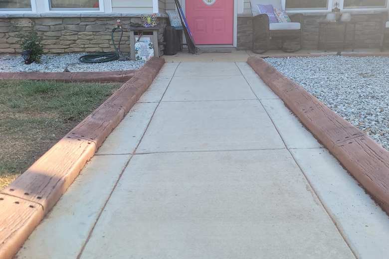Tan concrete curbing lining both sides of a straight front walkway