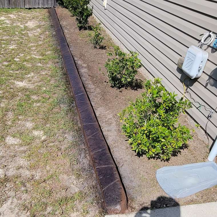 Straight run of wood-grain stamped curb along a planting bed with young shrubs