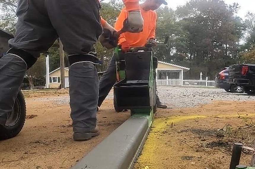 Killer Curbz crew extruding a continuous concrete curb with a curb machine at a Fayetteville, NC property